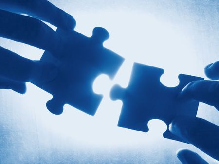 hands trying to fit two puzzle pieces together hands trying to fit two puzzle pieces together