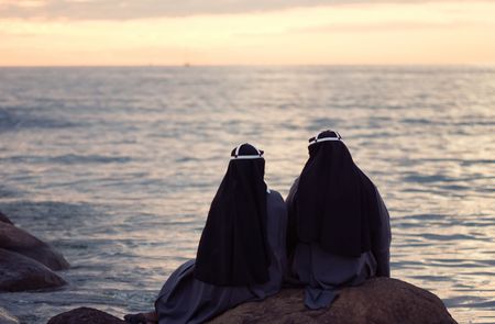 two nuns sitting at the stone on the shore of baltic seaの写真素材