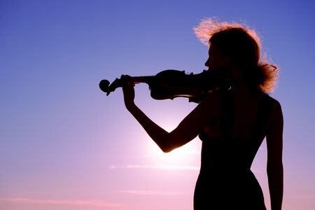 violin player performing solo at sunsetの写真素材