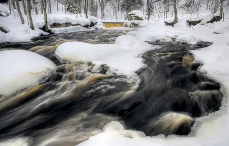 flowing winter waters at Nommeveski waterfall, Estoniaの写真素材