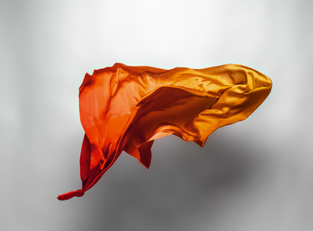 abstract piece of orange fabric flying, high-speed studio shotの写真素材