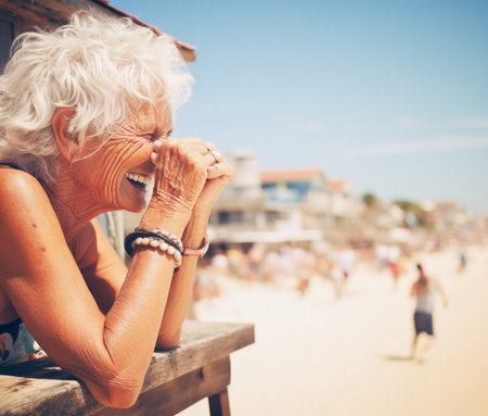 Happy retirement - Side view of happy senior Caucasian woman with hands clasped leaning on wooden railing at beach during summer; AI generatedの素材