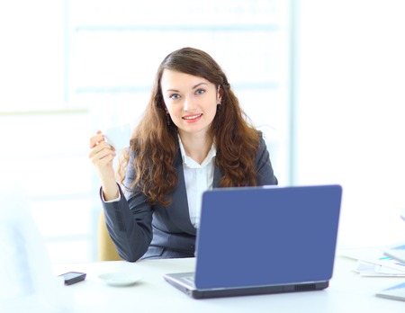 Thoughtful business woman in the office of the smiling drinking coffee.の写真素材