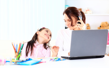 Young mother with little daughter sitting together at homeの写真素材