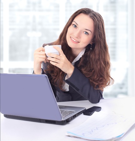 Beautiful businesswoman with a cup of coffee in the office.の写真素材
