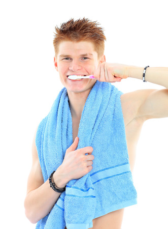 Reflection in a bathroom mirror of a young man brushing his teeth の写真素材