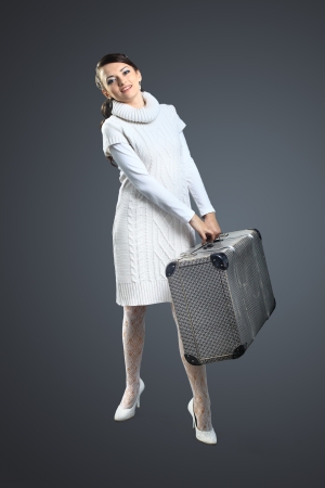 A beautiful girl with a suitcase in his hand. Isolated on a gray background.の写真素材