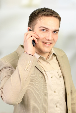 Young smiling businessman calling on phone at officeの写真素材