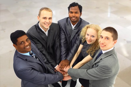 Portrait of friendly business team keeping their hands on top of each other and looking at camera の写真素材