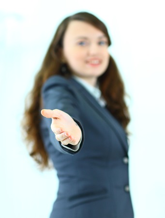 A beautiful young smiling business woman, happy and smiling , with an open hand ready to seal a deal or saying welcome. Isolated on a white background.の写真素材