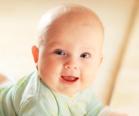 A cute baby girl in fairy wings laughs while looking up at the camera.の写真素材