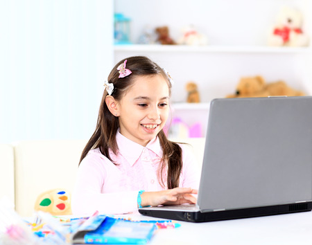 Cute little girl smiling and looking at laptop,Little girl using laptopの写真素材