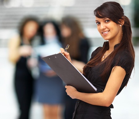 Charming girl holding a folder and looking at camera with a smileの写真素材