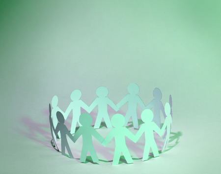 Team of paper doll people holding handsの写真素材