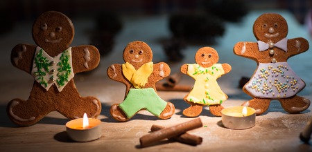 Christmas gingerbread men candles with cinnamon stars Pine twig Christmas ball on a wooden floorの写真素材