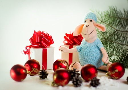 toy lamb with Christmas balls and fir paws giftsの写真素材