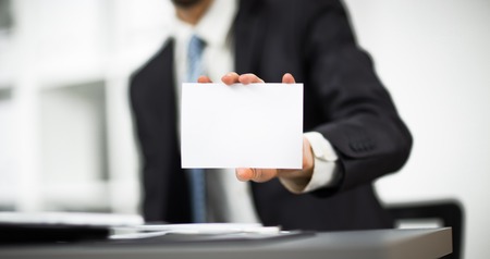 Man's hand showing business card - closeup shot on grey backgroundの写真素材