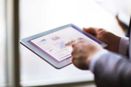 Business person analyzing financial statistics displayed on the tablet screen
