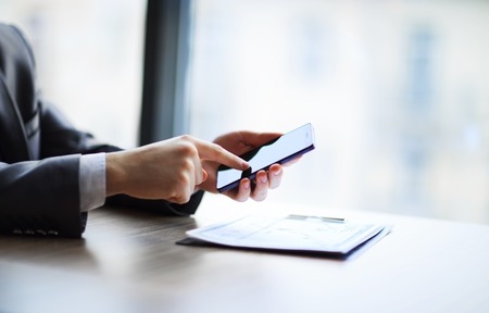 Close up of a man using mobile smart phone in officeの写真素材