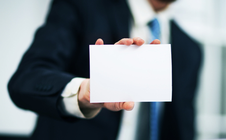 Man's hand showing business card - closeup shot on grey backgroundの写真素材