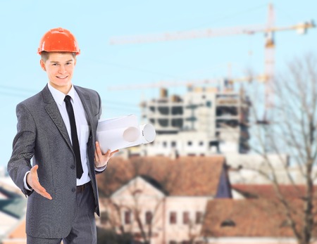 Engineer With Red Hard Hat and Blueprint Under the Power Lines.Engineer holding blueprints at an...