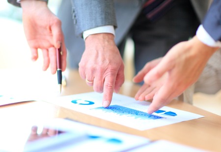 Close up of hands of managers discussing diagram and sitting at the tableの写真素材