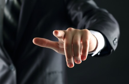 Businessman hand pressing an imaginary button on the virtual screen  a black background