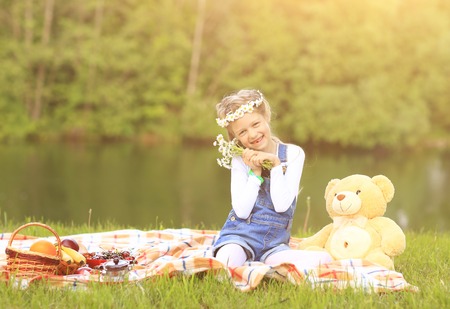 beautiful girl in a wreath with a Teddy bear on a picnicの写真素材