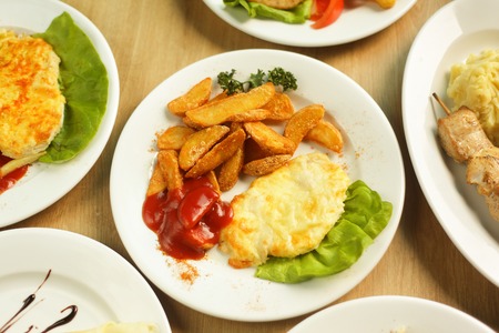 chicken in cheese with a side dish and lots of tasty dishes on the table in the restaurantの写真素材