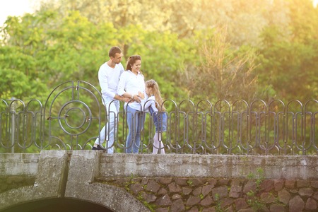 pregnant woman with her daughter and husband on a walk in the Park on a Sunny dayの写真素材