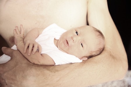 portrait of a newborn baby in the arms of his fatherの写真素材