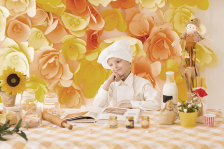cute little baby is preparing tasty meals at the kitchenの写真素材