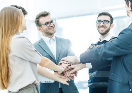 concept of success in business: friendly business team standing in a circle and joining his hands...