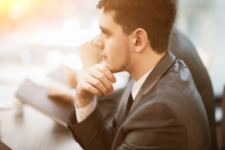 Casual businessman thinking with team behind him in officeの写真素材