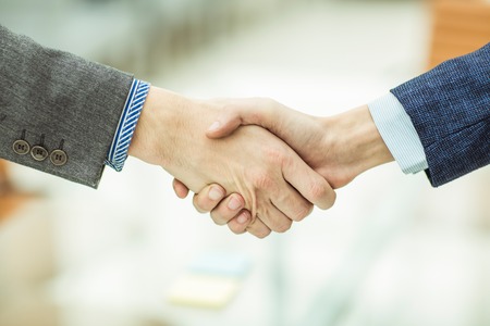 concept of a reliable partnership: a handshake of business partners on blurred light backgroundの写真素材