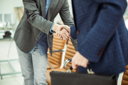 employees of the company with briefcases shaking hands in the lobby of a modern officeの写真素材