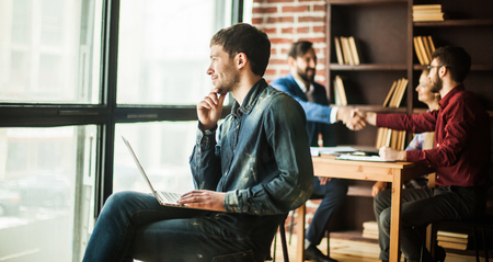 employee of the company with laptop looking out the windowの写真素材