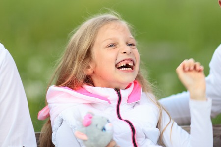 happy little girl with soft toy sitting on a Park