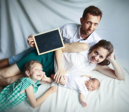 happy family: father ,mother and daughter holding a greeting carの写真素材