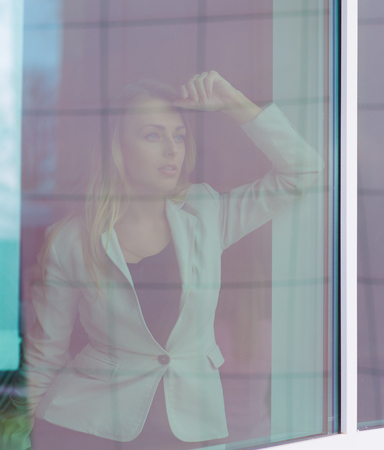 successful woman leader looks out the window of his personal office