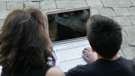 rear view.a couple of students looking at the laptop screen.の写真素材