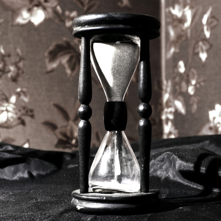 closeup.hourglass with white sand on a wooden tableの写真素材