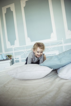happy five year old girl jumping on the bedの写真素材