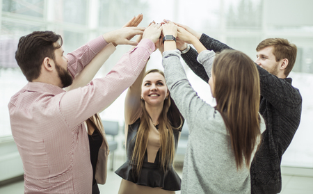 concept of teamwork:friendly business team standing in a circle and raising their handsの写真素材