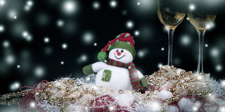 fun toy snowman and two glasses of champagne on a black backgroの写真素材