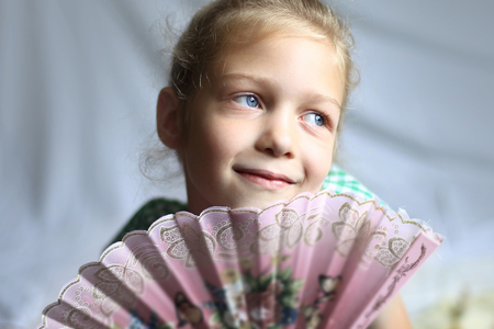 portrait - cute on bright background little girl with a fanの写真素材