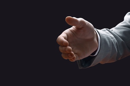 closeup. businessman holding out hand for a handshake while sitting at his Deskの写真素材