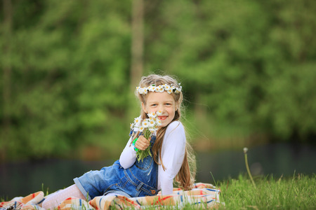 portrait of cute little girl in a wreath and a bouquet of wildflの写真素材