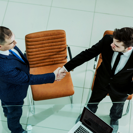 handshake business partners near the desktop, in the spacious officeの写真素材