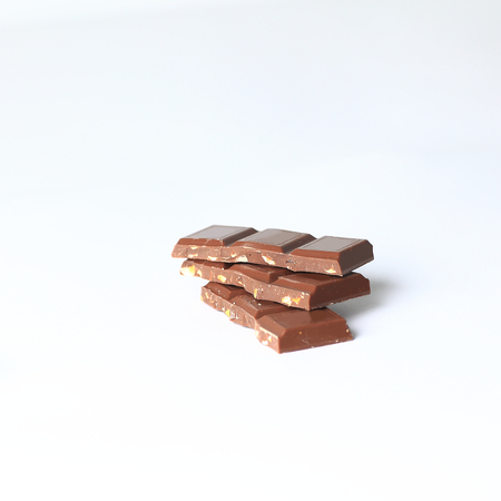 pieces of milk chocolate with nuts isolated on whiteの写真素材